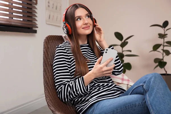 Mulher ouvindo audiolivro em cadeira em casa — Fotografia de Stock