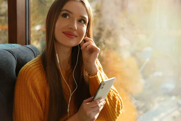 Γυναίκα ακούγοντας audiobook κοντά στο παράθυρο στο καφέ — Φωτογραφία Αρχείου