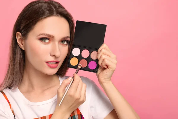 Beauty blogger with brush and eyeshadow palette on pink backgrou — Stok fotoğraf