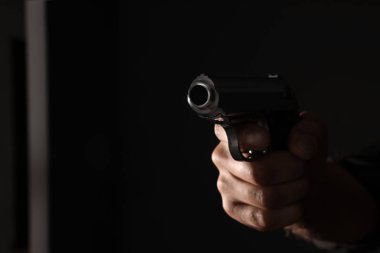 Siyah arka planda silahı olan profesyonel bir katil, yakın plan. Boşluk