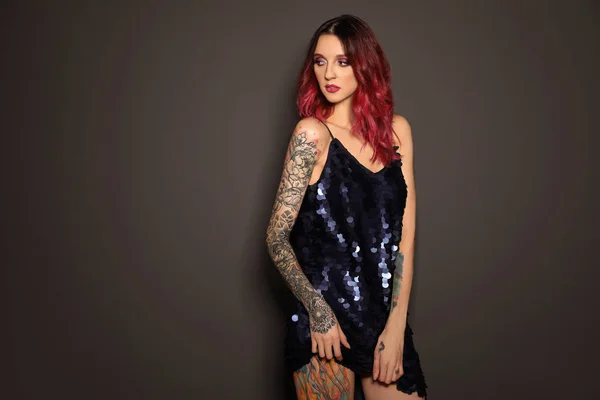 Beautiful woman with tattoos on body against black background
