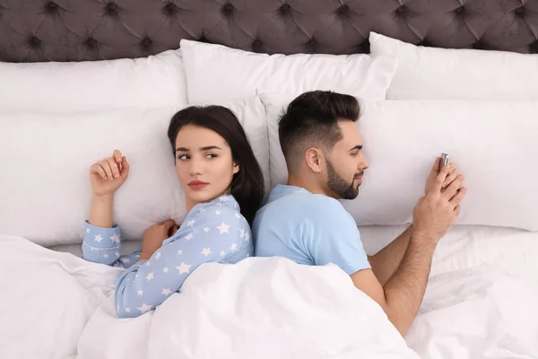 年轻人喜欢在床上用智能手机，而不喜欢在床上用女朋友 — 图库照片