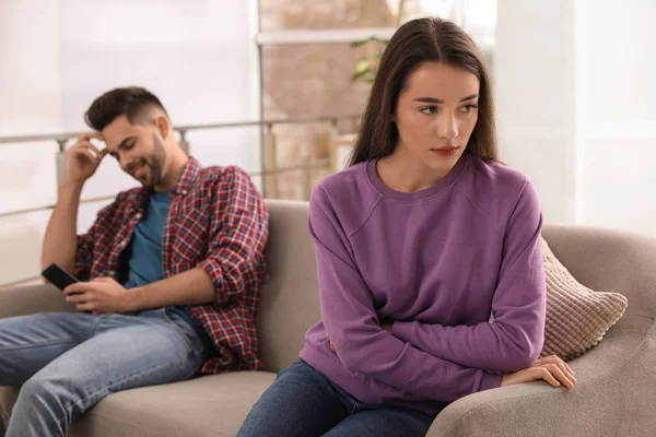 Hombre joven prefiriendo el teléfono inteligente sobre su novia en el sofá en — Foto de Stock