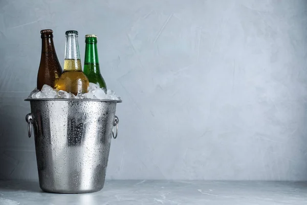 Beer in metal bucket with ice on marble table. Space for text