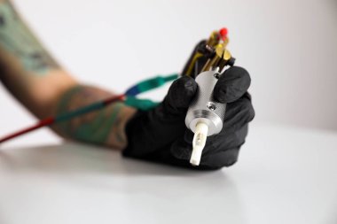 Masada ışık arkaplanına karşı profesyonel makineli dövme sanatçısı, yakın plan