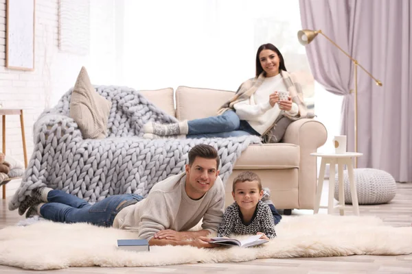 Otec a jeho syn číst knihy, zatímco matka odpočívá na pohovce — Stock fotografie