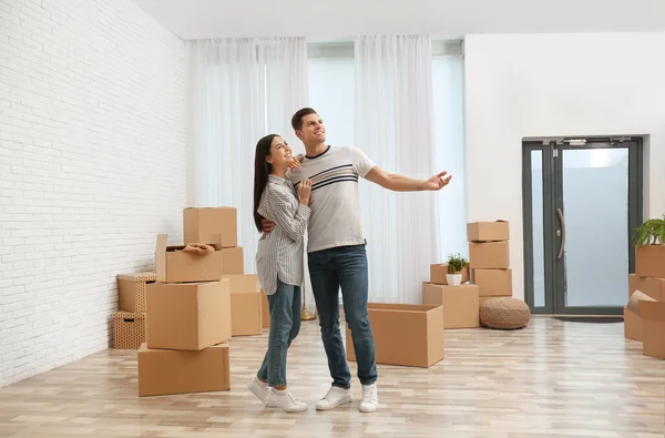 Pareja feliz en la habitación con cajas de cartón en el día en movimiento —  Fotos de Stock