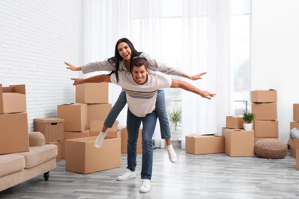 Feliz pareja divirtiéndose en la habitación con cajas de cartón en movimiento d —  Fotos de Stock