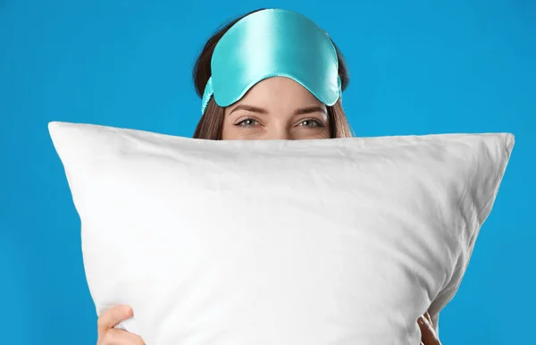 Beautiful woman with pillow on light blue background. Bedtime — Stock Photo, Image