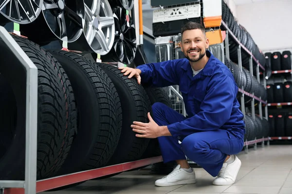 Male mechanic with car tires in auto store