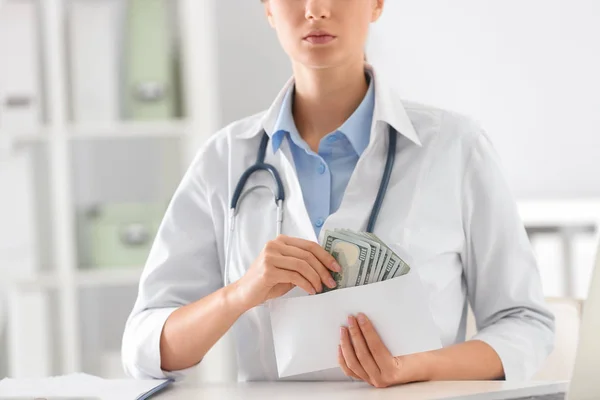 Doctor with bribe at desk in clinic, closeup. Corrupted medicine — 스톡 사진