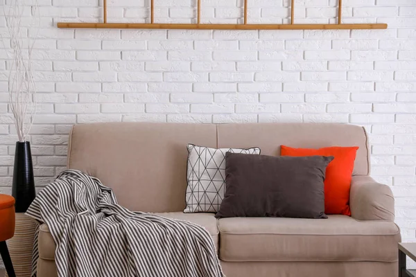 白いレンガの壁の近くのソファの上に柔らかい枕 — ストック写真