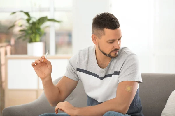 Man with nicotine patch and cigarette at home