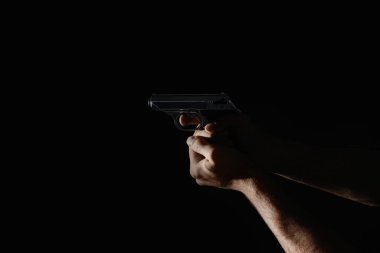 Siyah arka planda silahı olan profesyonel katil, yakın plan.
