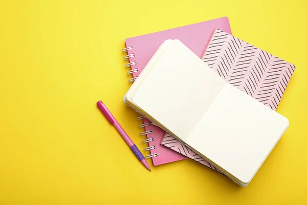 Cuadernos y bolígrafo con estilo sobre fondo amarillo, plano. Espacio — Foto de Stock