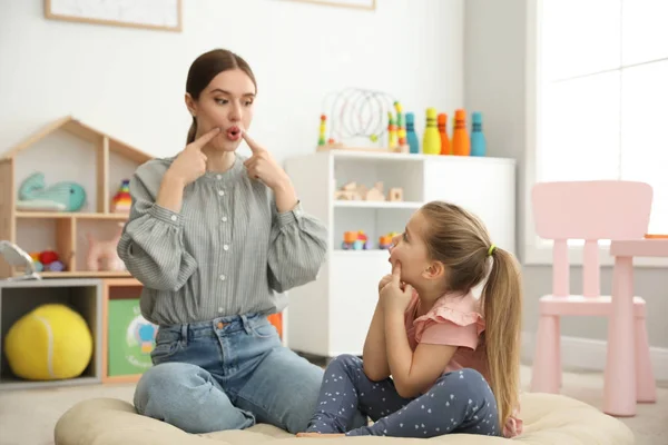 Speech therapist working with little girl in office