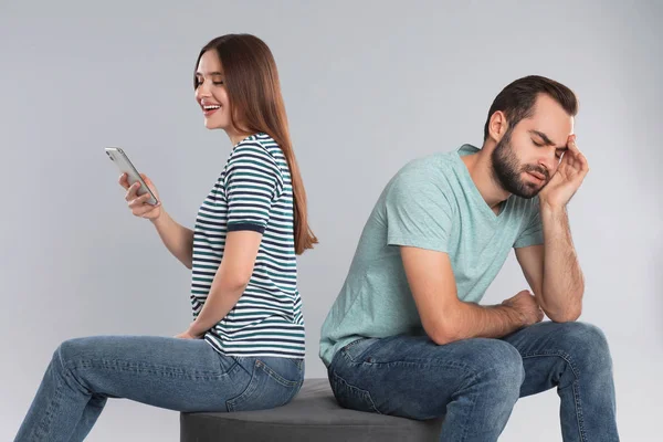 Kvinna Med Smartphone Ignorerar Sin Pojkvän Ljusgrå Bakgrund Relationsproblem — Stockfoto