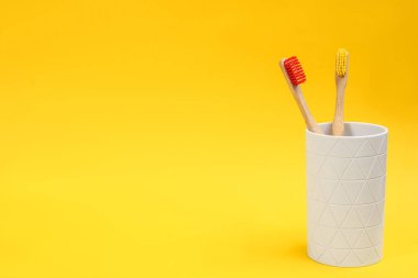 Sarı arka planda bambudan yapılmış diş fırçaları. Metin için boşluk