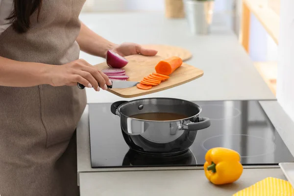 Young woman cooking tasty vegetable soup in kitchen, closeup — Stock Photo, Image