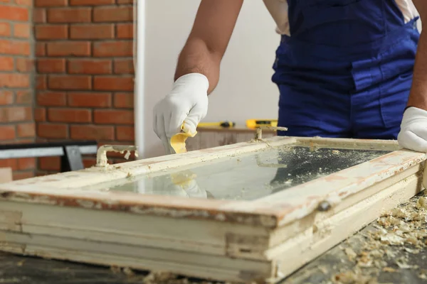 Man reparerar gamla skadade fönster vid bordet inomhus, närbild — Stockfoto
