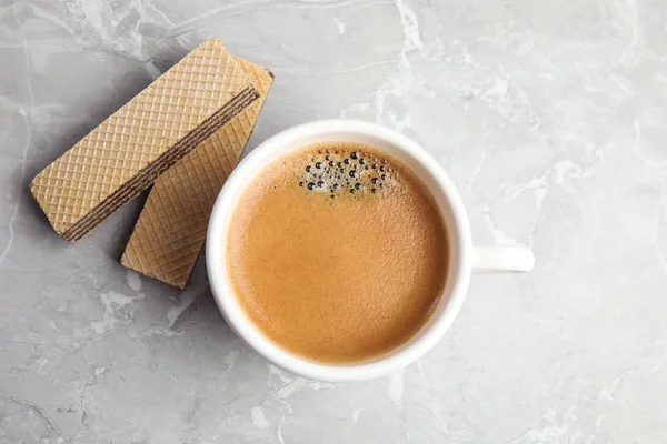 Delicious wafers and cup of coffee for breakfast on grey marble table, flat lay