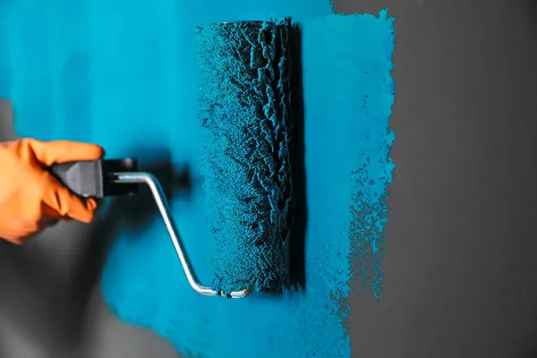 Žena malování šedá stěna s modrým barvivem, detailní záběr — Stock fotografie