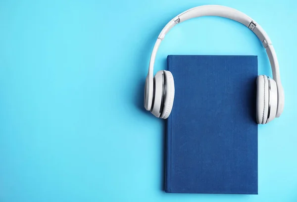 Libro y auriculares modernos sobre fondo azul claro, vista superior. S — Foto de Stock