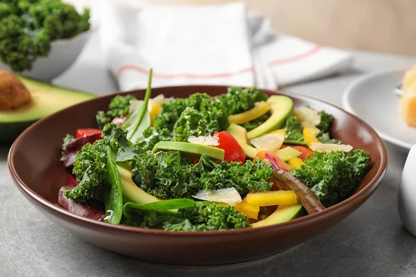 Tasty fresh kale salad on light grey table, closeup