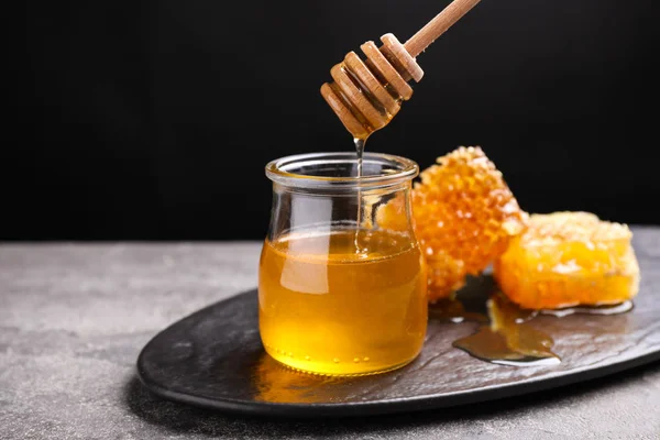 Honig Tropft Vom Löffel Ins Glas Auf Grauen Tisch — Stockfoto