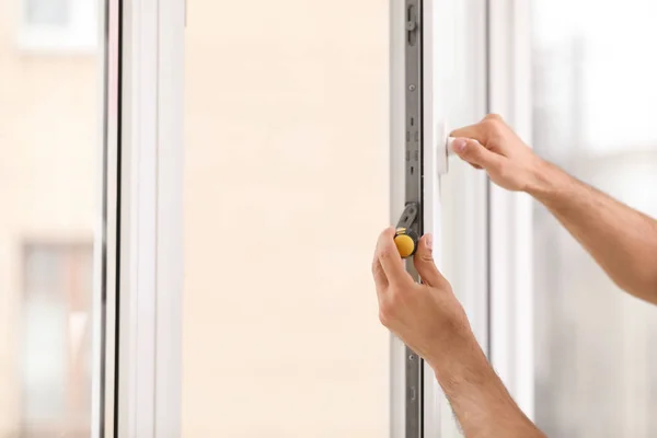 Construction worker repairing plastic window with screwdriver indoors, closeup