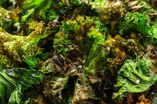 Tasty baked kale chips as background, closeup