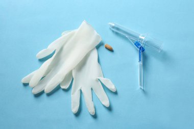 Anoskop, fitil ve lastik eldivenler açık mavi arka planda, düz yerde. Hemoroit tedavisi