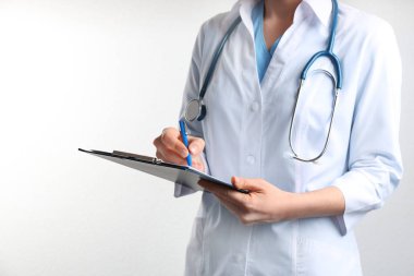 Beyaz arka planda steteskop ve panosu olan doktor, yakın plan. Tıbbi hizmet