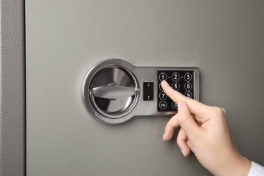 Çelik kasayı elektronik kilitle açan kadın, yakın plan.