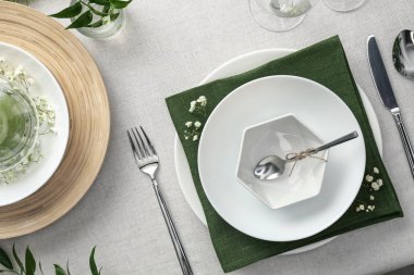 Açık renk kumaşlı yeşil bitkilerle süslü zarif bir masa.