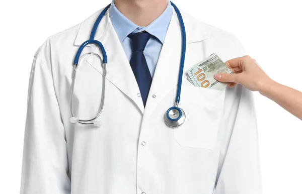 Paciente poniendo soborno en el bolsillo del médico sobre fondo blanco , —  Fotos de Stock
