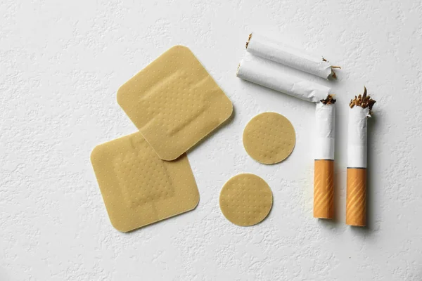 Nicotine patches and broken cigarettes on white background, flat lay