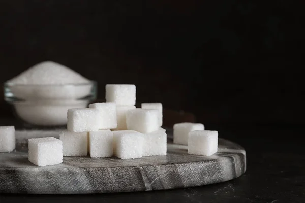 Heap of refined sugar cubes on black background