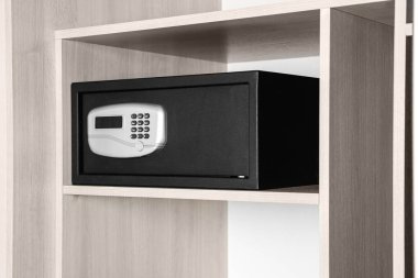 Ahşap dolapta elektronik kilit olan siyah çelik kasa.