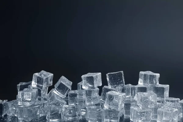 Crystal clear ice cubes with water drops against black background. Space for text