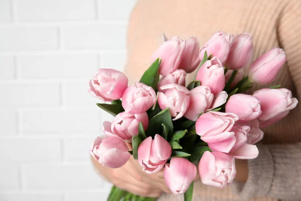 Mulher com belas tulipas de primavera rosa perto da parede de tijolo branco, c — Fotografia de Stock