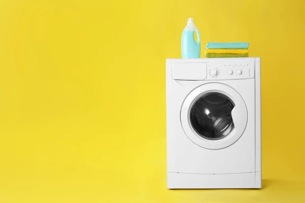 Lavadora moderna con pila de toallas y detergente en yel —  Fotos de Stock