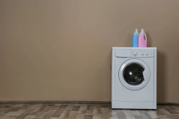 Lavadora moderna con detergentes cerca de la pared beige, espacio fo — Foto de Stock