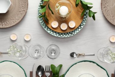 Beyaz ahşap döşeme üzerinde yeşil bitkiler olan zarif bir masa.