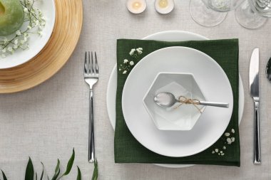 Açık renk kumaşlı yeşil bitkilerle süslü zarif bir masa.