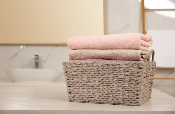 Корзина для белья со свежими полотенцами на столе в ванной комнате — стоковое фото