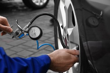 Tamirci araba servisinde lastik basıncını kontrol ediyor.