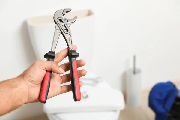 Encanador profissional segurando alicate contra vaso sanitário no banho — Fotografia de Stock