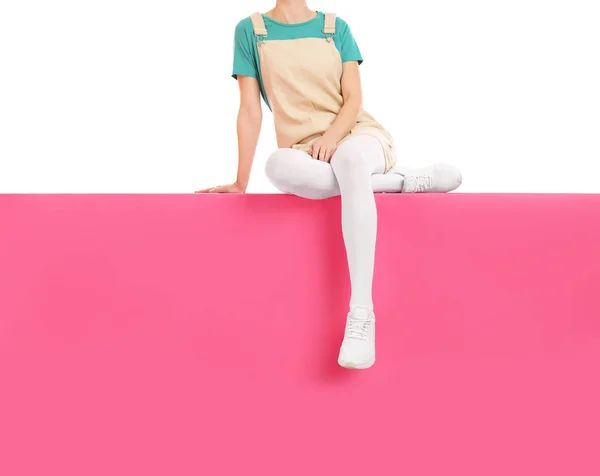 Woman wearing white tights and stylish shoes sitting on color ba — 스톡 사진
