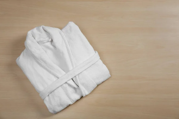 Clean folded bathrobe on wooden background, top view. Space for — Stock Photo, Image